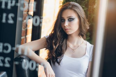 Zarif beyaz elbiseli uzun saçlı Genç güzel esmer kız. Gün batımında akşamları şehrin sokaklarında yürüyen kadın.