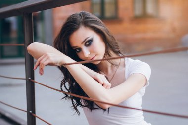 Zarif beyaz elbiseli uzun saçlı Genç güzel esmer kız. Gün batımında akşamları şehrin sokaklarında yürüyen kadın.