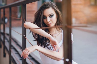 Zarif beyaz elbiseli uzun saçlı Genç güzel esmer kız. Gün batımında akşamları şehrin sokaklarında yürüyen kadın.