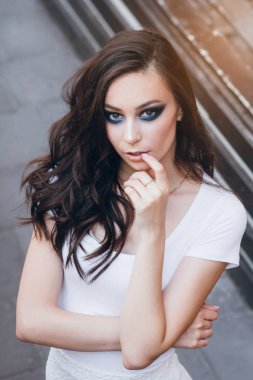 Zarif beyaz elbiseli uzun saçlı Genç güzel esmer kız. Gün batımında akşamları şehrin sokaklarında yürüyen kadın.