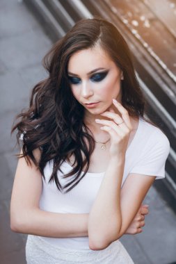 Zarif beyaz elbiseli uzun saçlı Genç güzel esmer kız. Gün batımında akşamları şehrin sokaklarında yürüyen kadın.