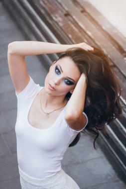 Zarif beyaz elbiseli uzun saçlı Genç güzel esmer kız. Gün batımında akşamları şehrin sokaklarında yürüyen kadın.