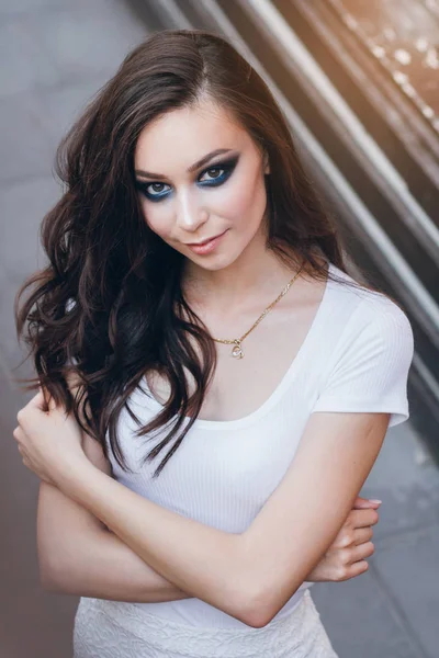 Zarif beyaz elbiseli uzun saçlı Genç güzel esmer kız. Gün batımında akşamları şehrin sokaklarında yürüyen kadın.