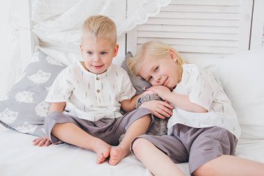 Küçük kız ve erkek kardeş kıyafetler içinde yatağa otur. Balonlar ile tatil. Tonlama.