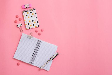 Not defteri ve kalem pembe bir arka plan üzerinde. Düz yatıyordu kompozisyon. Masanın üzerinde ofis, banka donatımı.