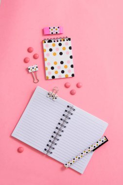 Not defteri ve kalem pembe bir arka plan üzerinde. Düz yatıyordu kompozisyon. Masanın üzerinde ofis, banka donatımı.