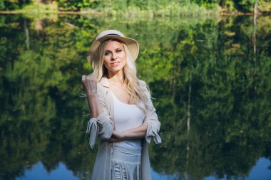 Köprüde sonbahar göl kenarında oturan şapkalı güzel genç sarışın kız. Tonlama.