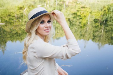 Köprüde sonbahar göl kenarında oturan şapkalı güzel genç sarışın kız. Tonlama.