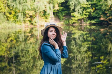 Köprüde sonbahar göl kenarında oturan şapkalı güzel genç kız. Tonlama.