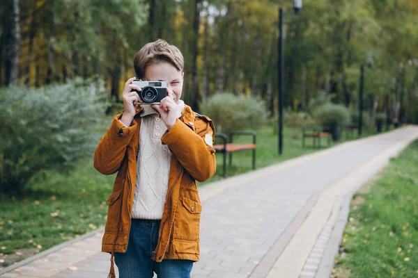 可爱的男孩走在一个五颜六色的秋天公园和姿势 这个男孩在镜头里拍照 — 图库照片