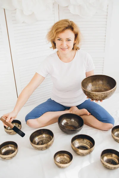Massage therapist plays on singing bowls for a vibrational massage in the Spa. The concept of relaxation and alternative medicine. Toning.
