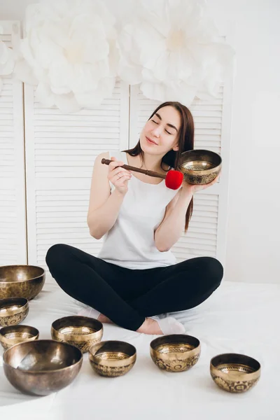 Massage therapist plays on singing bowls for a vibrational massage in the Spa. The concept of relaxation and alternative medicine. Toning.