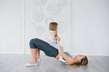 Genç sportif anne ve bebek kız egzersizleri birlikte spor yapın. Üst ve alt sağlıklı geliştirme, fitness ve dinlenme. Sağlıklı yaşam konsepti fotoğraf. Tonlama.