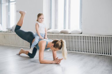 Genç sportif anne ve bebek kız egzersizleri birlikte spor yapın. Üst ve alt sağlıklı geliştirme, fitness ve dinlenme. Sağlıklı yaşam konsepti fotoğraf. Tonlama.