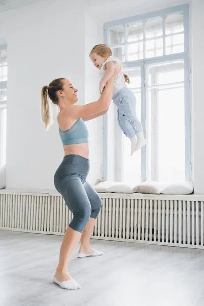 Genç sportif anne ve bebek kız egzersizleri birlikte spor yapın. Üst ve alt sağlıklı geliştirme, fitness ve dinlenme. Sağlıklı yaşam konsepti fotoğraf. Tonlama.