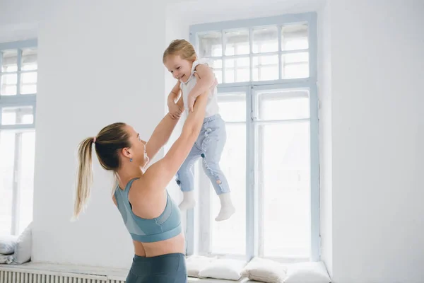 Genç sportif anne ve bebek kız egzersizleri birlikte spor yapın. Üst ve alt sağlıklı geliştirme, fitness ve dinlenme. Sağlıklı yaşam konsepti fotoğraf. Tonlama.