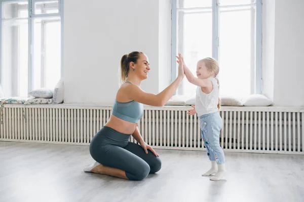 Genç sportif anne ve bebek kız egzersizleri birlikte spor yapın. Üst ve alt sağlıklı geliştirme, fitness ve dinlenme. Sağlıklı yaşam konsepti fotoğraf. Tonlama.