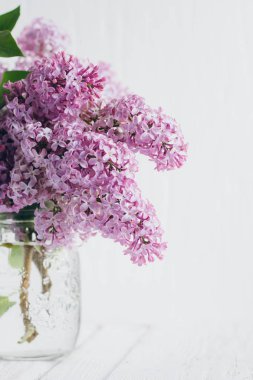 Beyaz ahşap bir masa üzerinde bir vazoda yemyeşil leylak buket. Tonlama garanti et. Seçici odak.