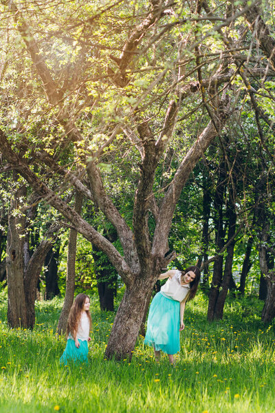 Мать и маленькая дочь ходят весной цветущие яблоки
 