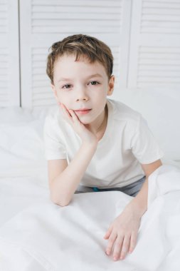 Sevimli çocuk sabah ve uykulu oturan yatakta uyandım 