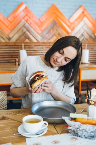 Kobieta jedząca świeżo przygotowane pyszne hamburgery — Zdjęcie stockowe