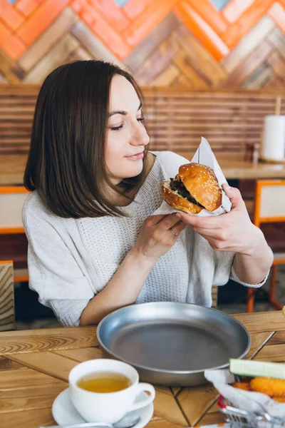 Kobieta jedząca świeżo przygotowane pyszne hamburgery — Zdjęcie stockowe