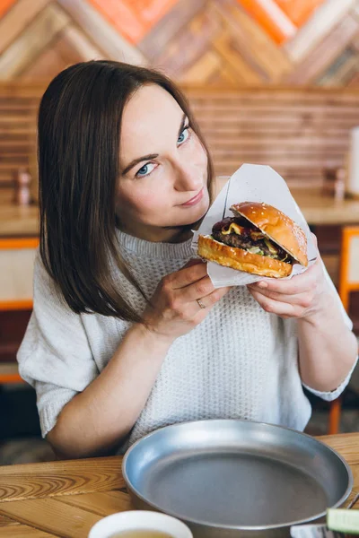 Nainen syö juuri valmistettua herkullista Burgeria — kuvapankkivalokuva