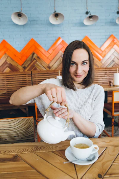 Kobieta wlewa zieloną herbatę z czajnika do filiżanki w kawiarni — Zdjęcie stockowe