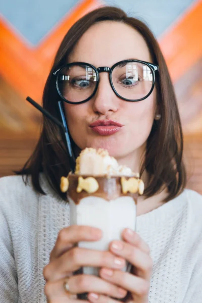 Kobieta pije milkshake pięknie zdobione śmietaną i ciasteczkami — Zdjęcie stockowe