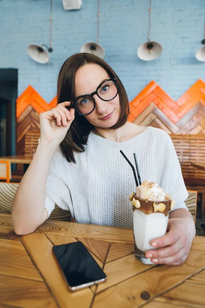 Kobieta pije milkshake pięknie zdobione śmietaną i ciasteczkami — Zdjęcie stockowe