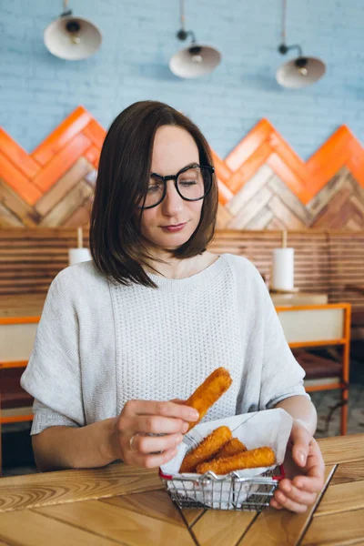 ผู้หญิงกินแท่งชีสทอดในคาเฟ่ — ภาพถ่ายสต็อก
