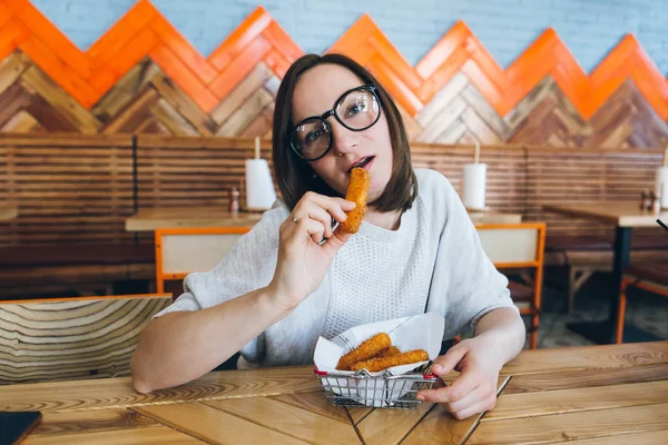 La mujer come palitos de queso frito en un café — Foto de Stock