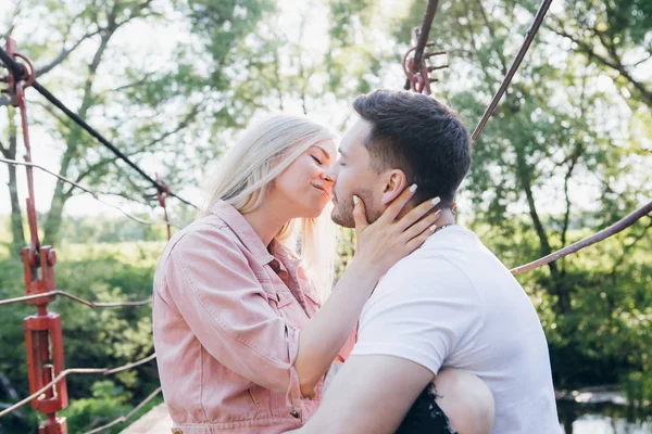 Joven pareja chico y chica en el puente sobre el río y beso —  Fotos de Stock