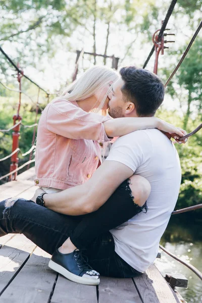 Молодая пара парень и девушка на мосту через реку и поцелуй — стоковое фото