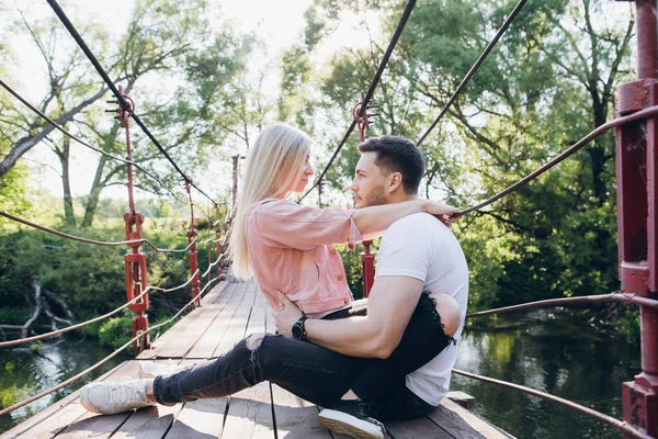 Joven pareja chico y chica en el puente sobre el río y beso —  Fotos de Stock