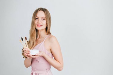 Yararlı bir bambu diş fırçası ve diş tozu bir kavanoz tutan kız