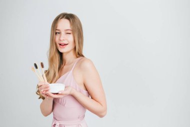 Yararlı bir bambu diş fırçası ve diş tozu bir kavanoz tutan kız