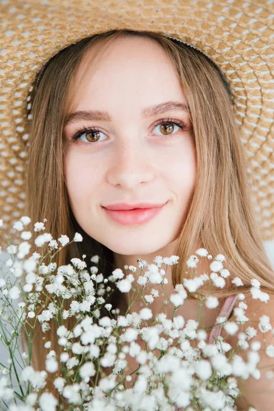 白い花の花束でポーズをとる長い髪と帽子を持つ女の子 — ストック写真