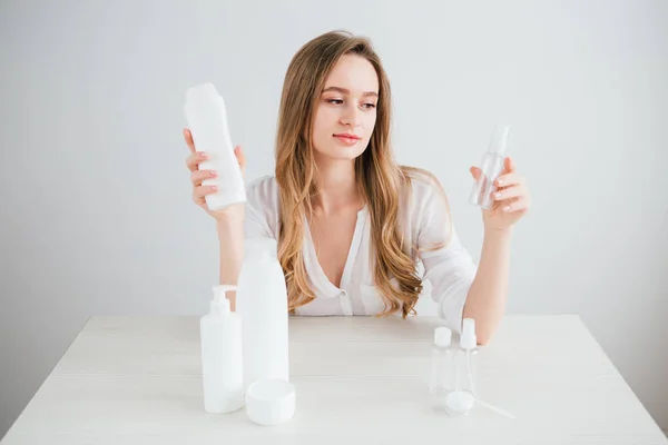 Girl compares the size of cosmetic bottles for travel to save space in the suitcase