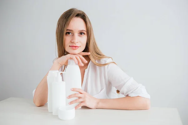 Joven hermosa chica con botellas de cosméticos blancos de diferentes tamaños — Foto de Stock