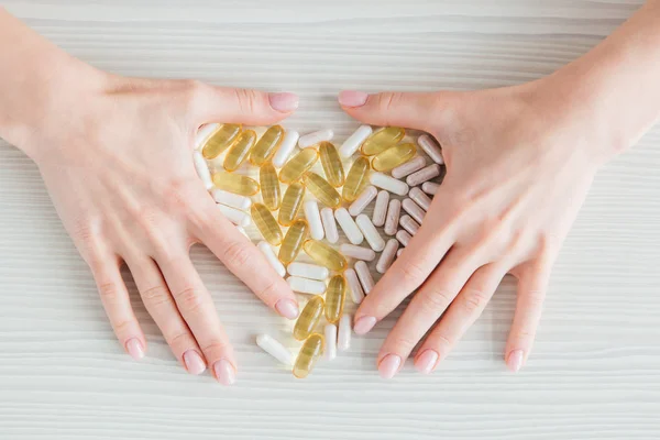 Muchas cápsulas coloridas de tabletas, vitaminas, suplementos dietéticos en la mano en un primer plano de mesa blanca — Foto de Stock