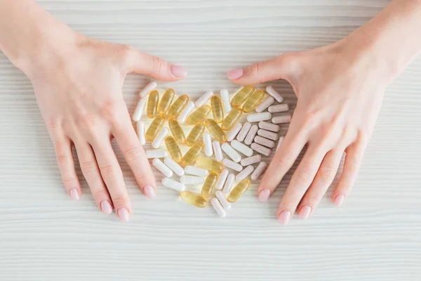 Muchas cápsulas coloridas de tabletas, vitaminas, suplementos dietéticos en la mano en un primer plano de mesa blanca — Foto de Stock