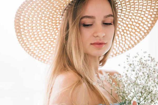 흰 꽃다발을 들고 포즈를 취하는 긴 머리와 모자를 쓴 소녀 — 스톡 사진