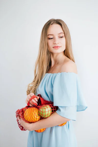 Joven hermosa chica con fruta fresca en una bolsa de hilo — Foto de Stock