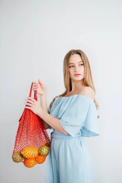 Joven hermosa chica con fruta fresca en una bolsa de hilo — Foto de Stock