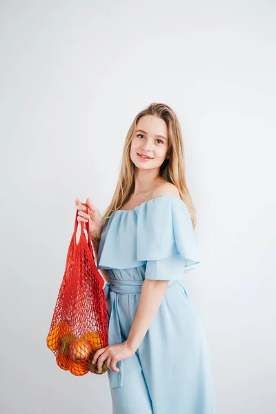 Joven hermosa chica con fruta fresca en una bolsa de hilo — Foto de Stock