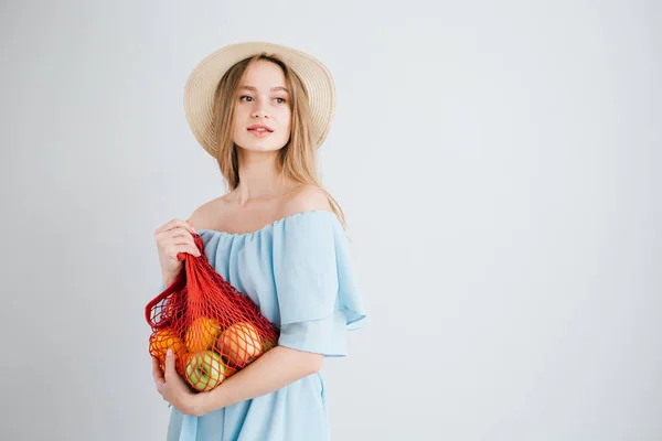 Young beautiful girl with fresh fruit in a string bag