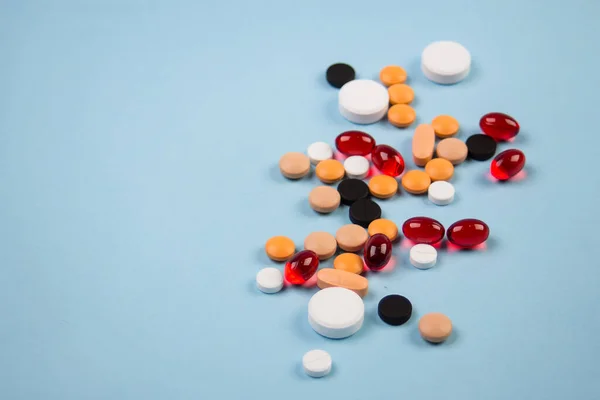 Tabletták különböző színű egy kék háttér — Stock Fotó