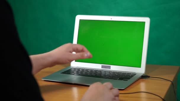 Una persona que usa una computadora portátil sentada encima de una mesa — Vídeos de Stock