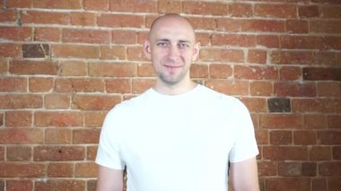 Tuğla duvarın önünde duran bir adam.